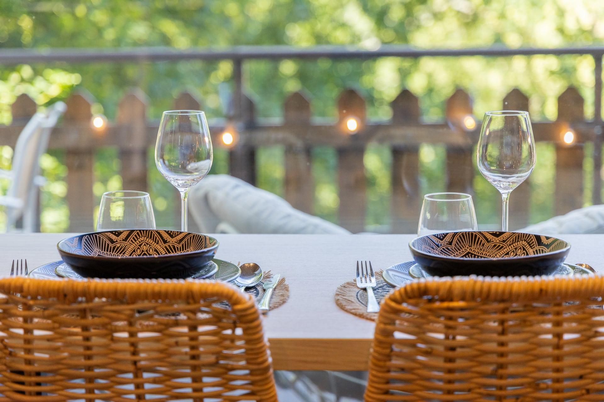 Table set for two, with the terrace and trees in the background