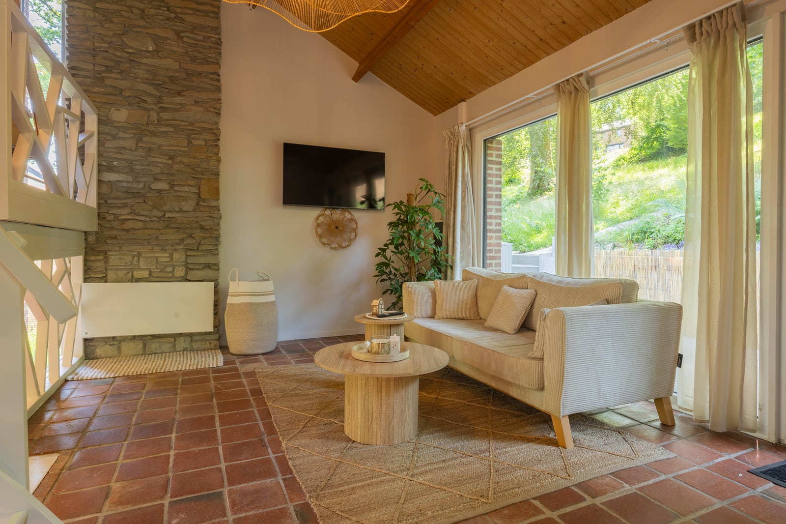 Bright living room with a sofa, natural stone and large windows